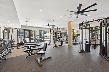 A gym with a variety of equipment including treadmills, weights, and a bench press. at The Concord Luxury Apartments, Sarasota